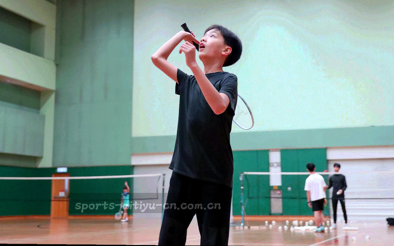 俯拍球场夜景，草皮与看台灯光拉出斜向光带，右侧留出大片暗部